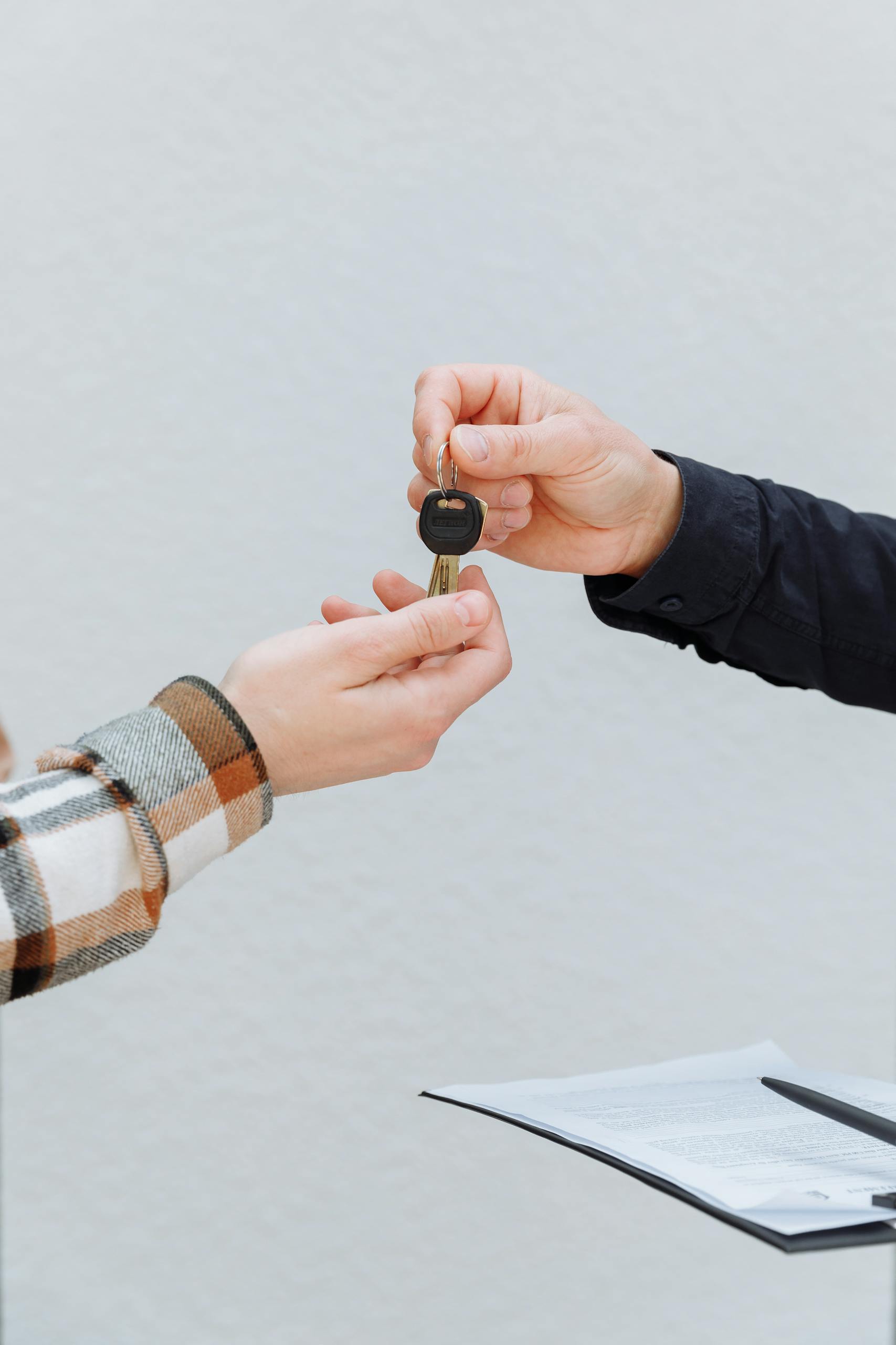 Close-up of hands exchanging car keys, symbolizing a business transaction.